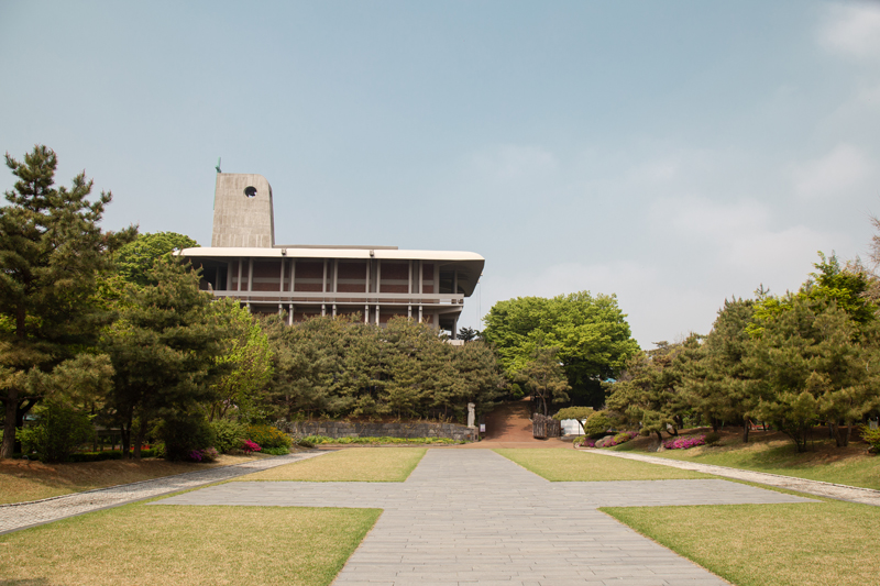 십자가 모양을 한 잔디길 뒤에 한국천주교순교자박물관이 보인다